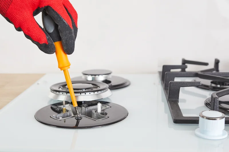 Repairman fixing a modern white gas stove cooktop burner Repairman fixing a modern white gas stove cooktop burner