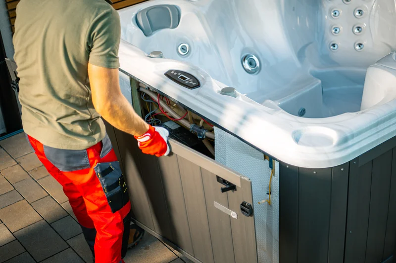 Maintenance worker servicing internal components of an outdoor hot tub spa.
