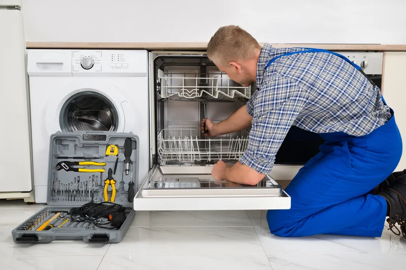 Technician in kitchen repairing open dishwasher near washing machine. Technician in kitchen repairing open dishwasher near washing machine.