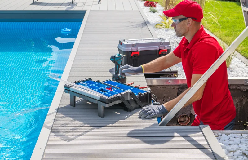 Pool technician repairing pool equipment on a grey composite deck.