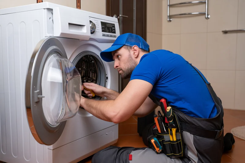 Appliance repair technician servicing a front-load washing machine. Appliance repair technician servicing a front-load washing machine.