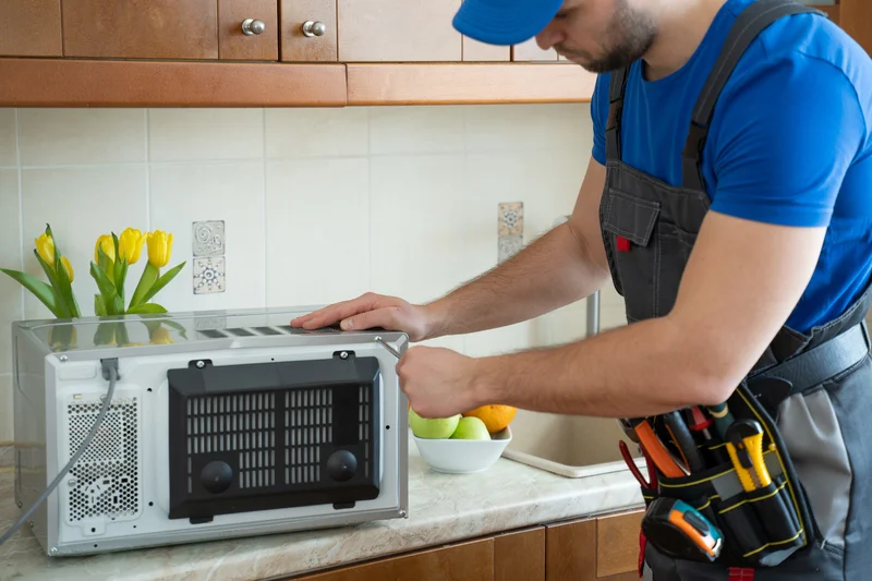 Professional appliance repair technician fixing a microwave oven.