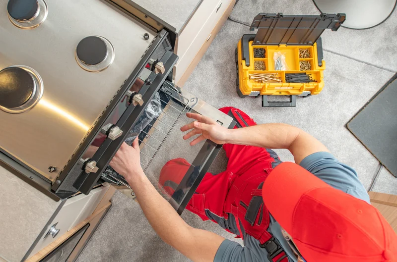 Appliance repair technician fixing a modern stainless steel oven Appliance repair technician fixing a modern stainless steel oven
