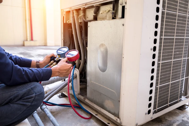 HVAC service technician measuring pressure on outdoor AC unit HVAC service technician measuring pressure on outdoor AC unit